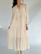 Woman wearing a beige striped dress against a white background