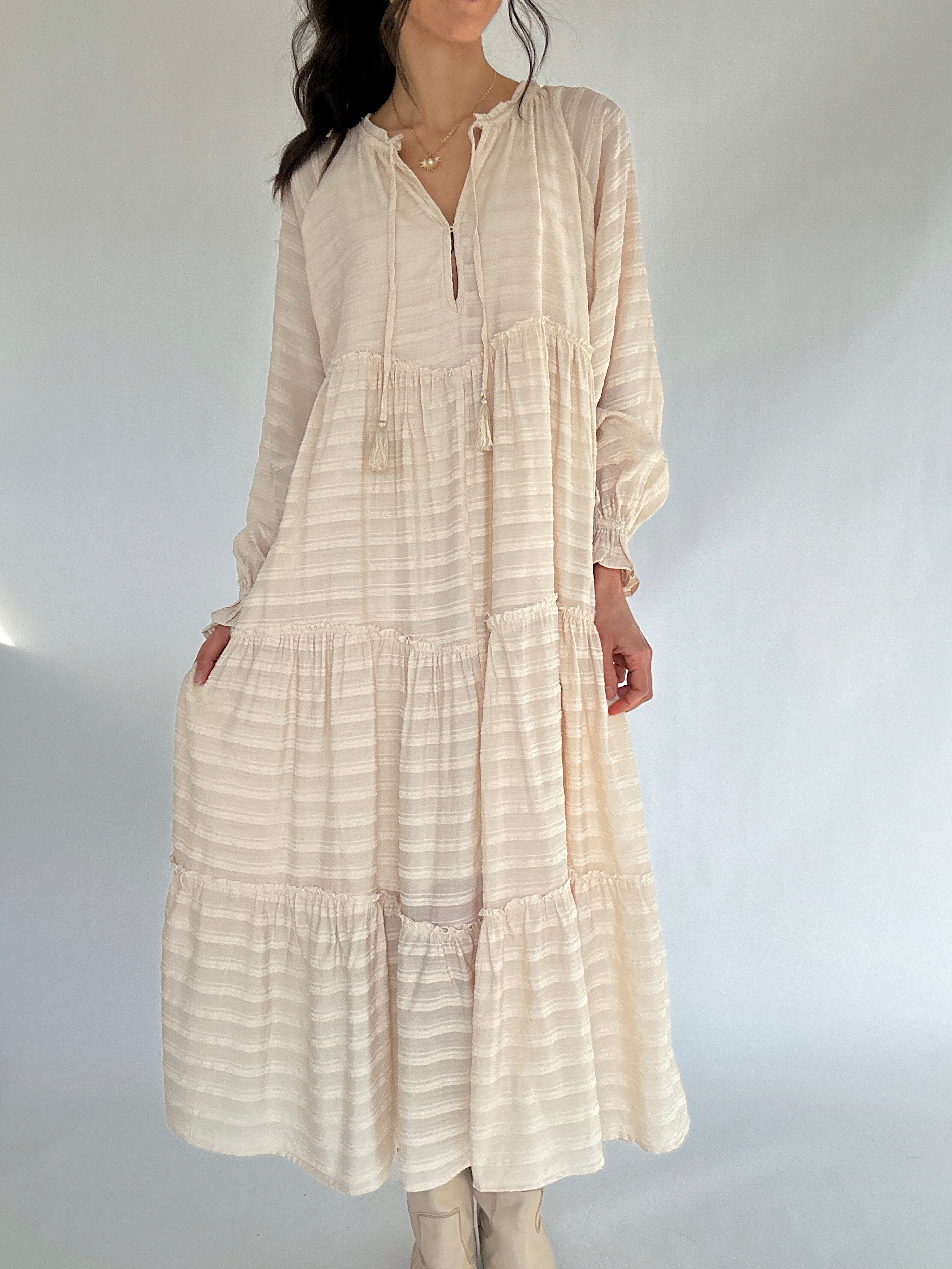 Woman wearing a beige striped dress against a white background