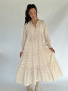 Woman wearing a beige long dress with a white background