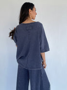 Person wearing a blue textured outfit against a white background showing the back