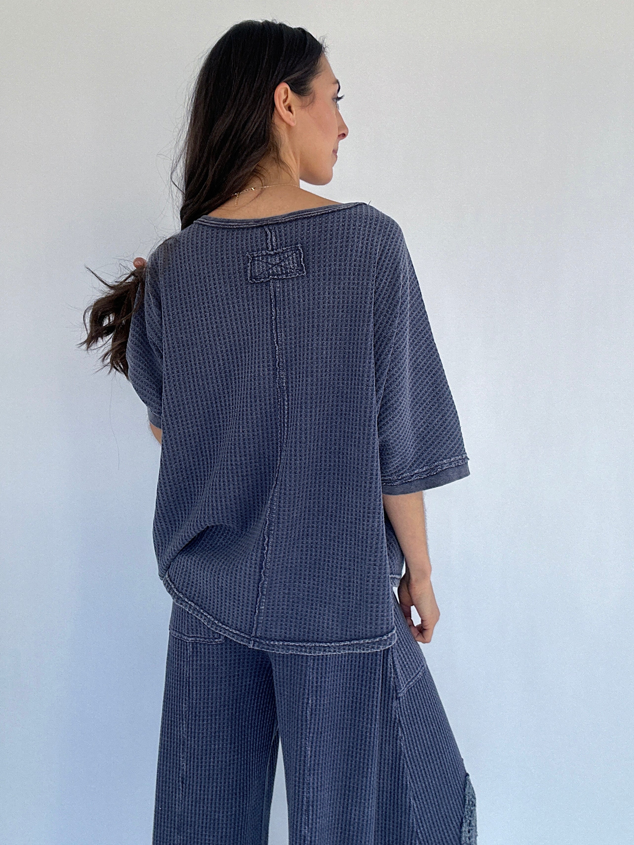 Person wearing a blue textured outfit against a white background showing the back