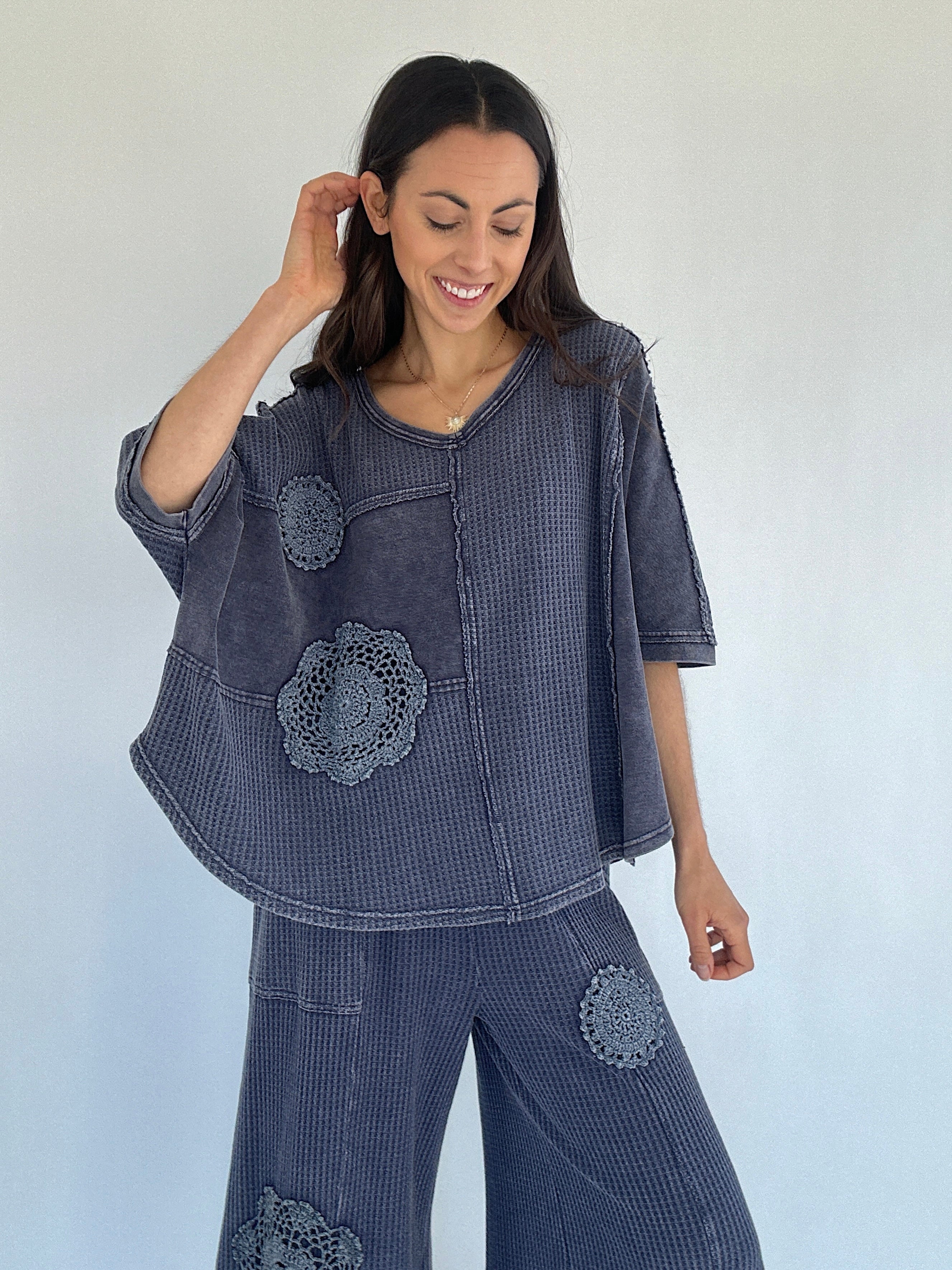 Woman wearing a midnight blue textured outfit with floral patterns against a white background