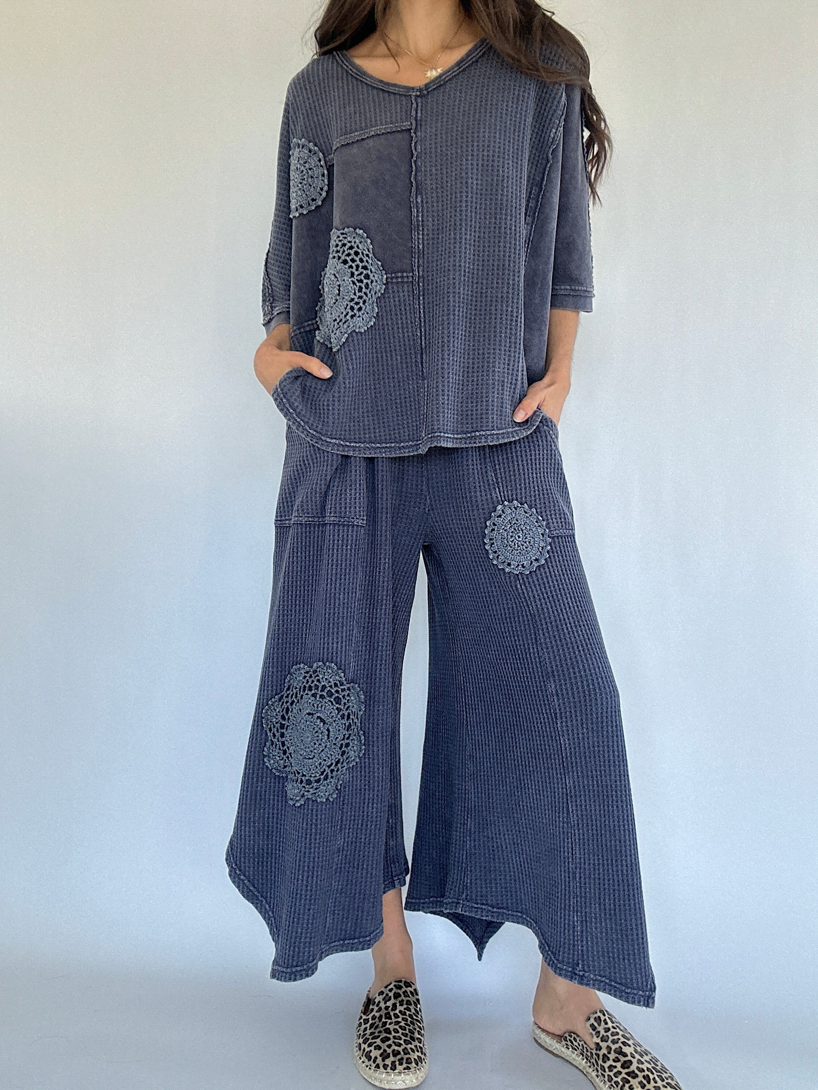 Person wearing a blue textured outfit with floral patterns on a white background