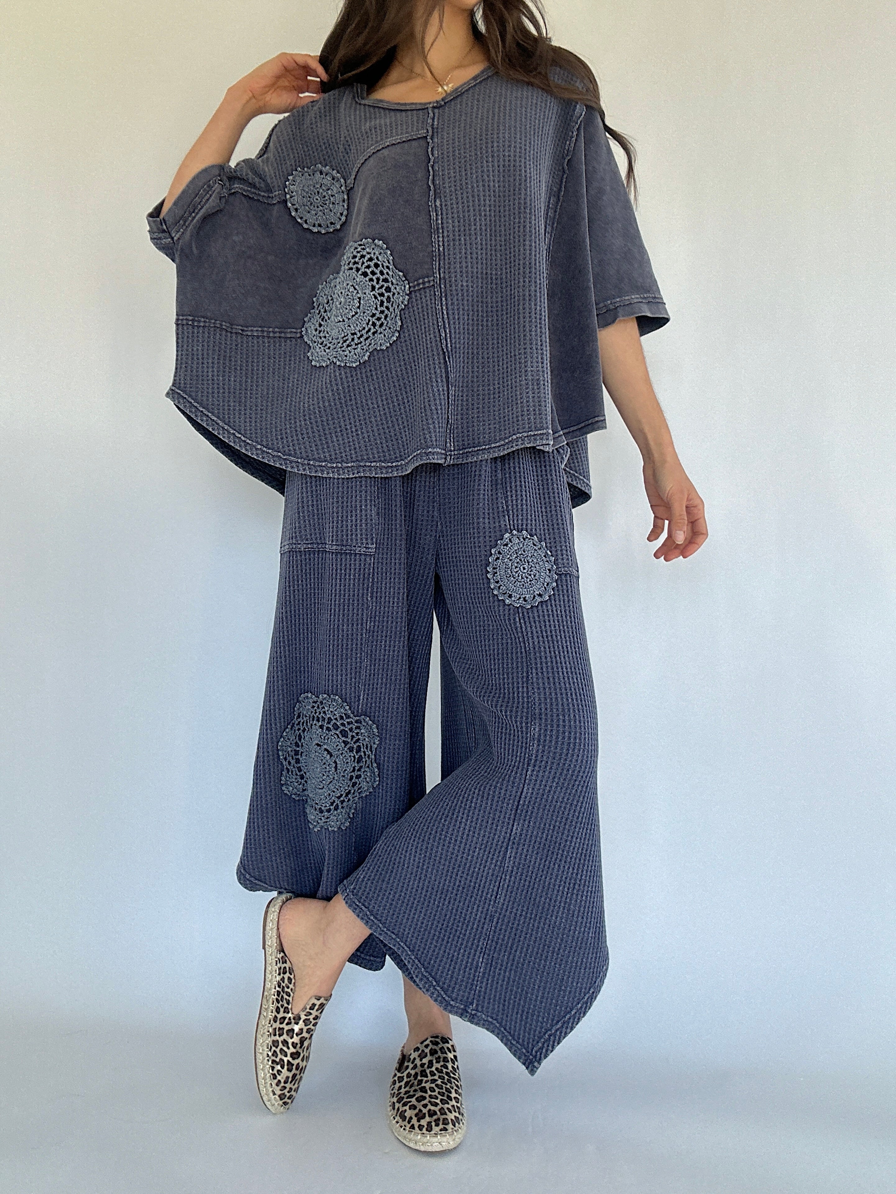 Person wearing a midnight blue textured outfit with floral crochet patterns on a white background