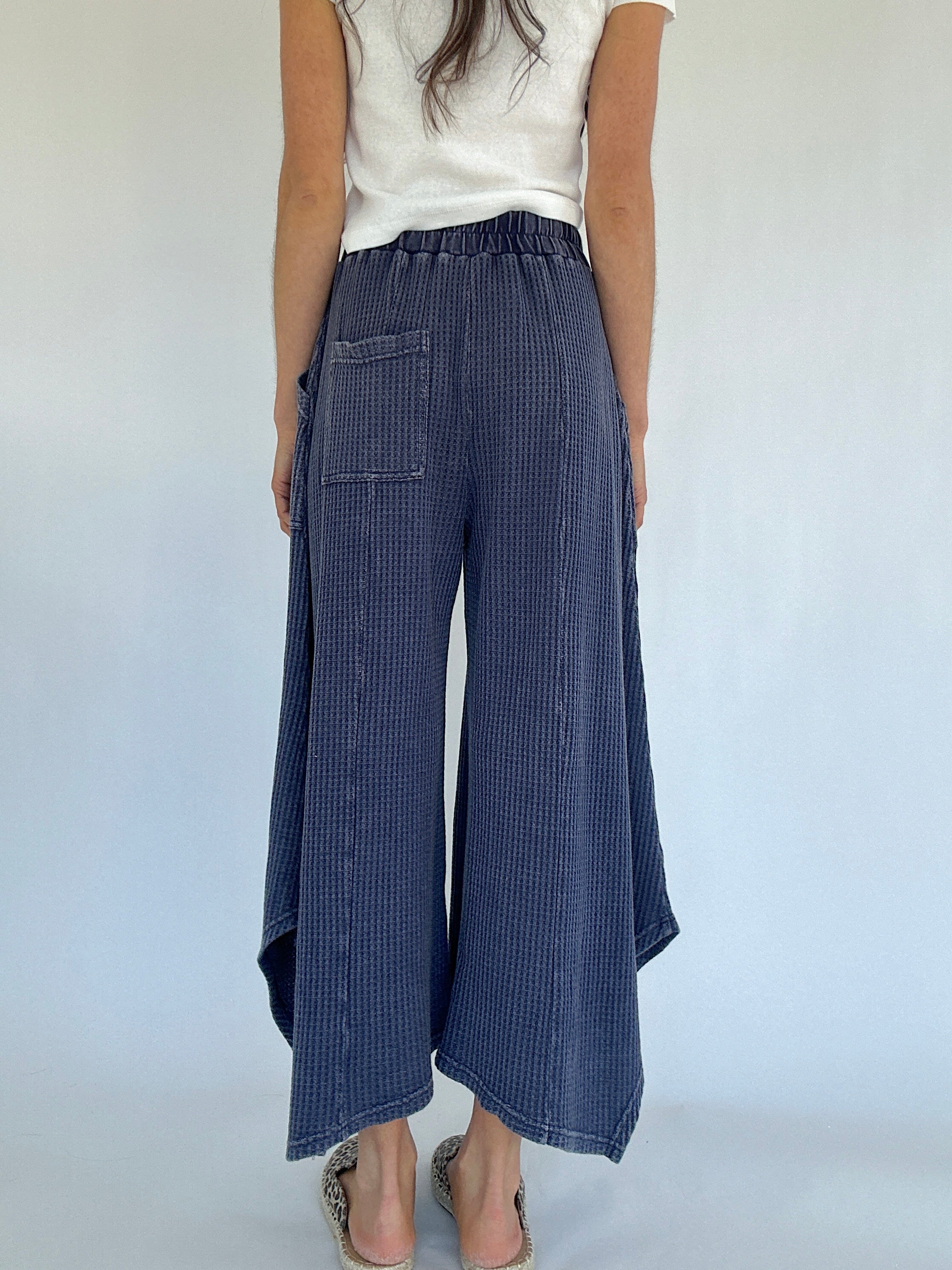 Person wearing blue waffle knit wide-leg pants on a white background showing back with one back pocket