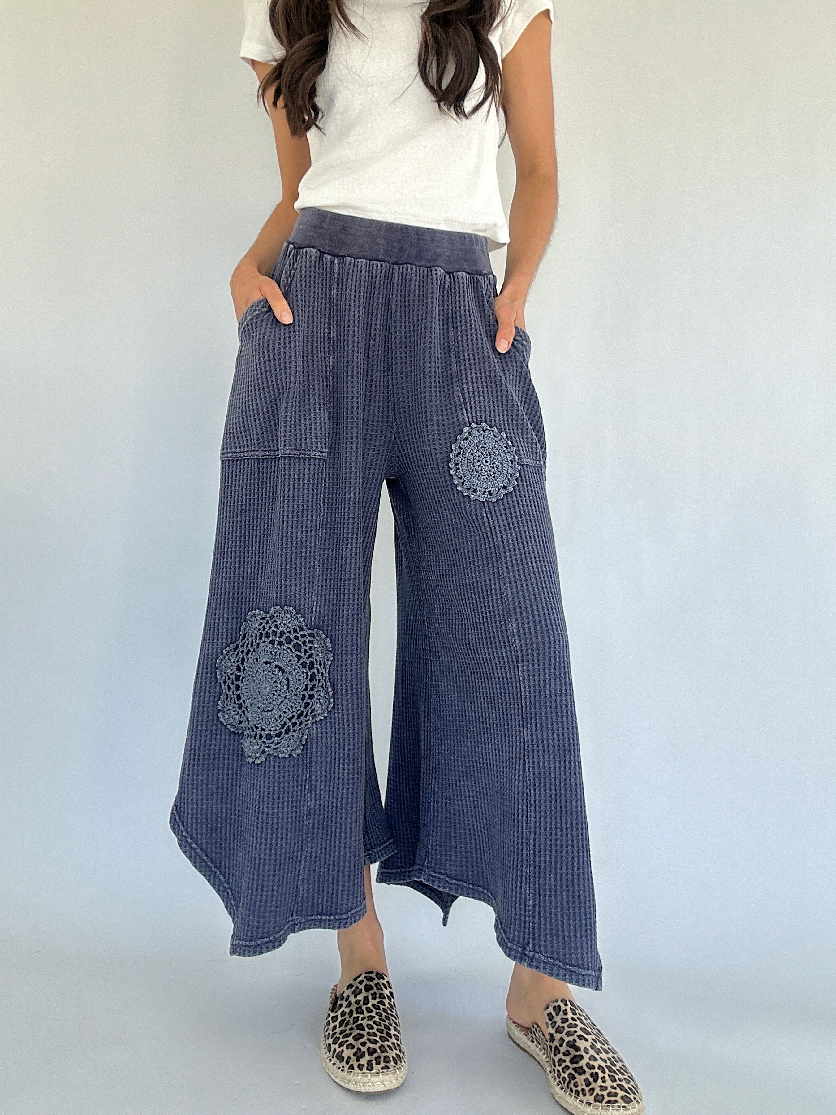 Person wearing midnight blue waffle knit  wide-leg pants with floral patches on a white background