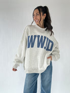Person wearing a gray mockneck sweatshirt with 'WWJD' printed in blue on a plain background