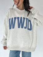 Person wearing a gray sweatshirt with 'WWJD' printed in blue on a plain background