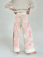 Person wearing a patterned pants and beige sweater on a plain background from back