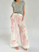 Person wearing a green top and floral patchwork pants on a plain background