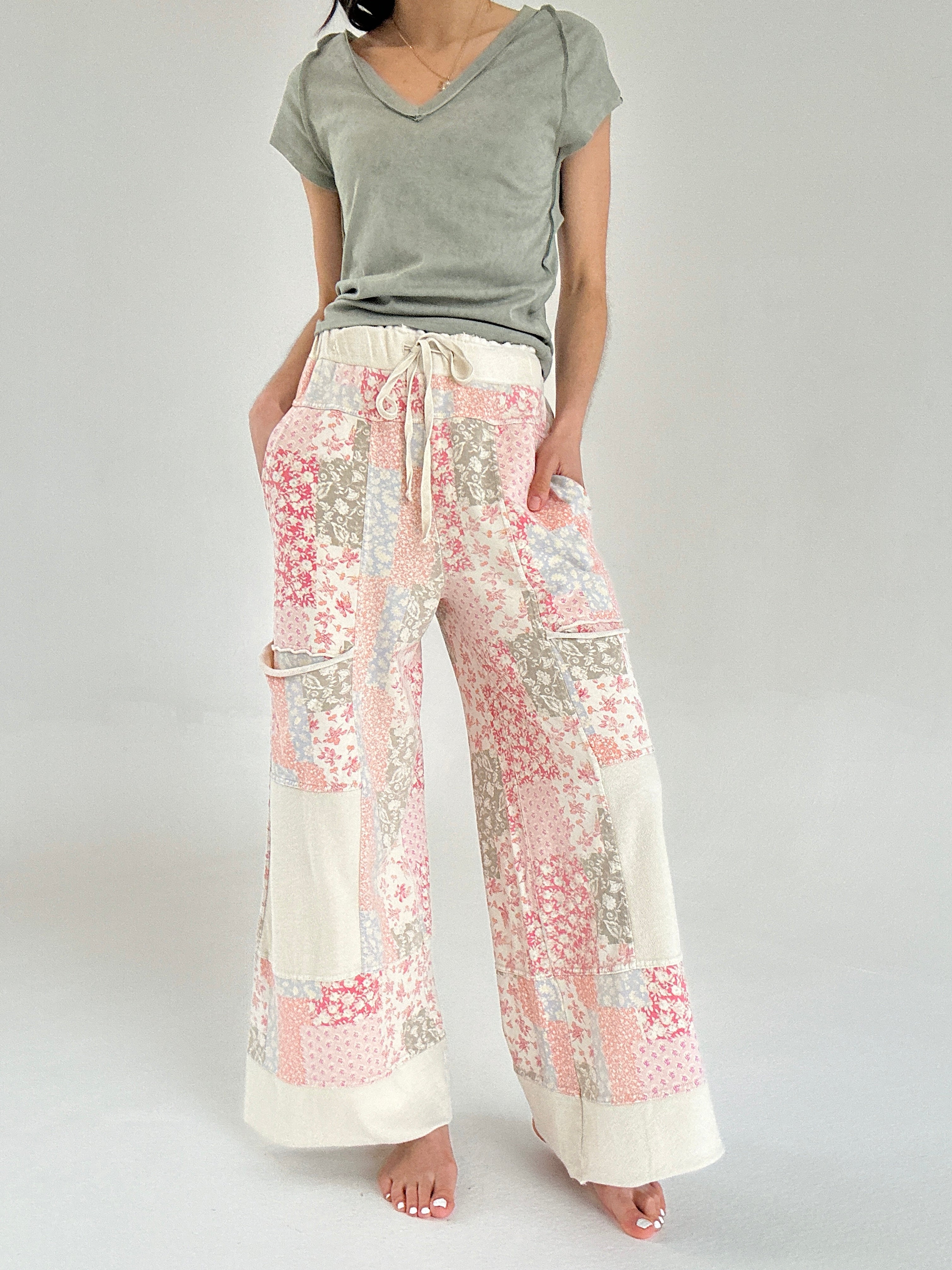 Person wearing a green top and floral patchwork pants on a plain background