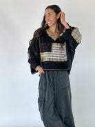 Woman wearing a black top with plaid American flag design and washed black wide leg pants against a white background