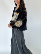 Woman wearing a black and gold patterned top with wide-leg pants against a white background