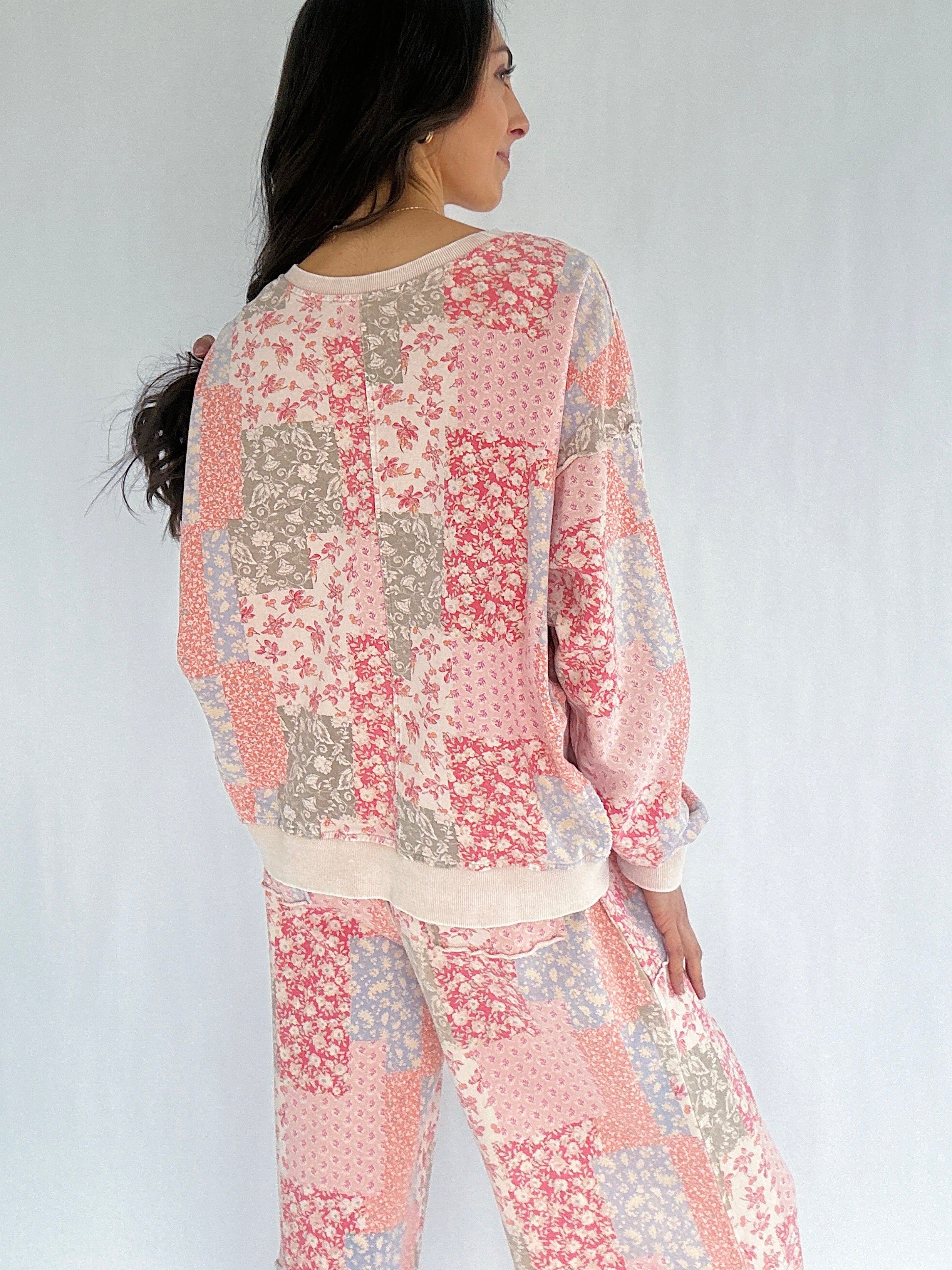 Woman wearing a floral patchwork patterned outfit on a plain background showing the back