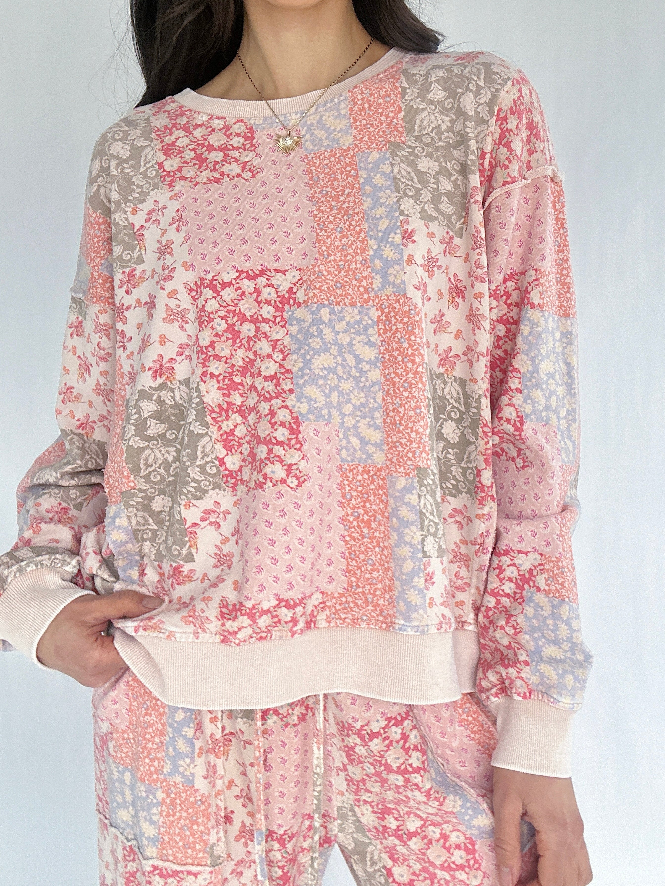 Person wearing a patchwork floral sweatshirt and pants on a white background