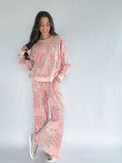 Woman wearing a pink and beige floral patchwork patterned matching outfit on a white background