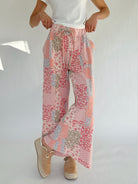 Person wearing a pair of patterned wide leg pants on a white background
