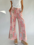 Person wearing floral patchwork pants on a plain background with hands in pockets