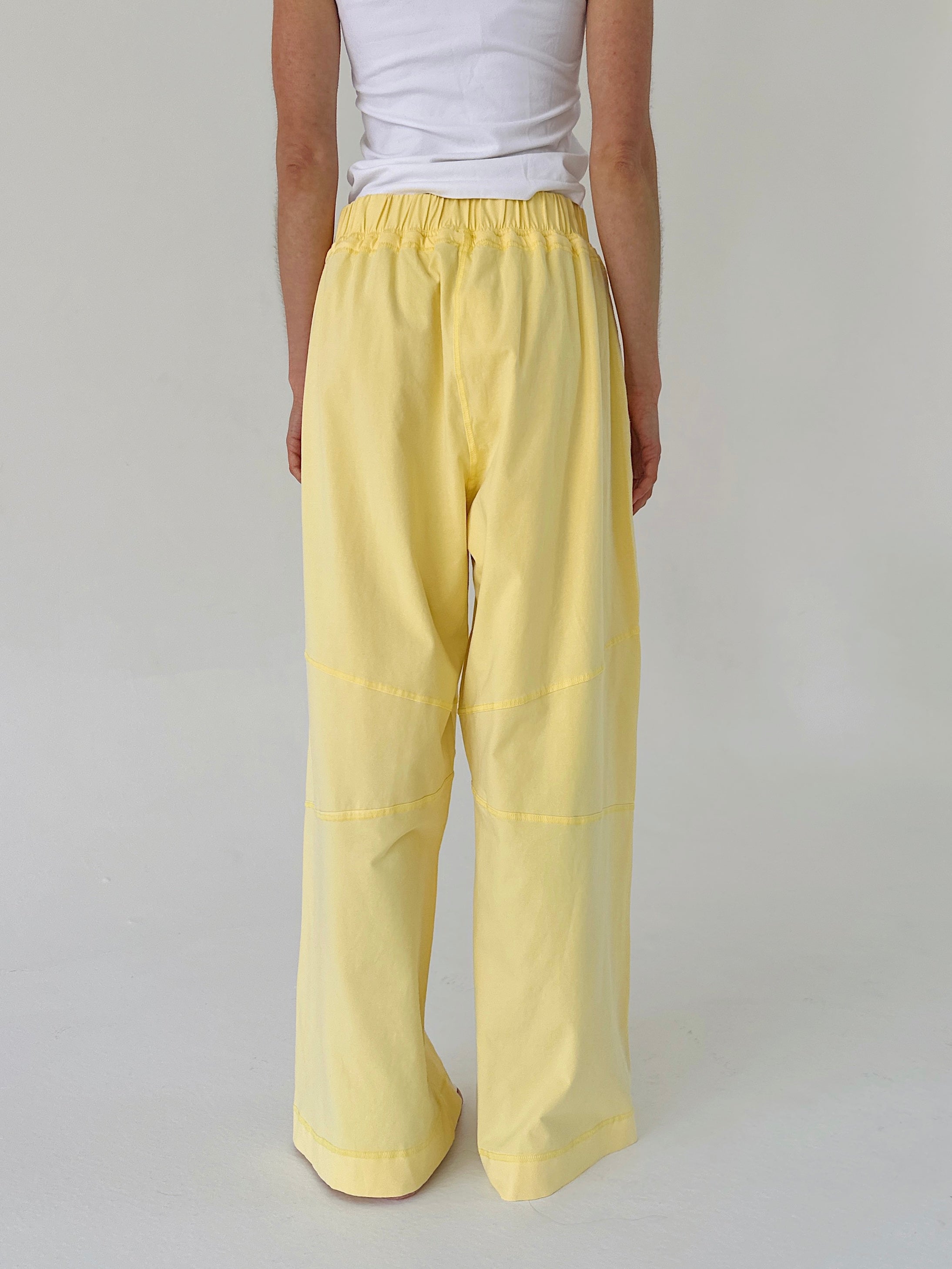 Person wearing yellow pants and a white top on a plain background
