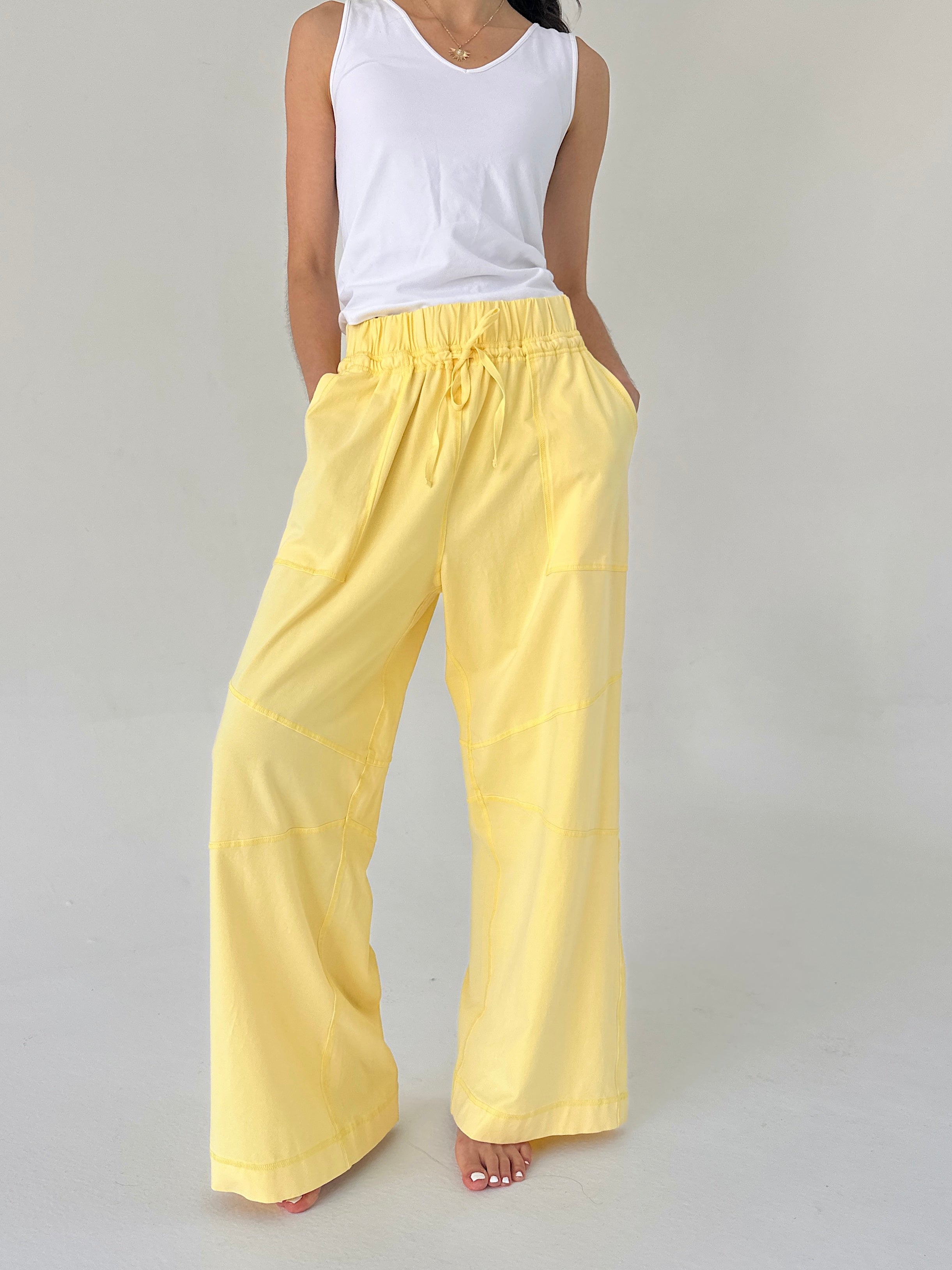 Person wearing yellow pants and a white top on a gray background