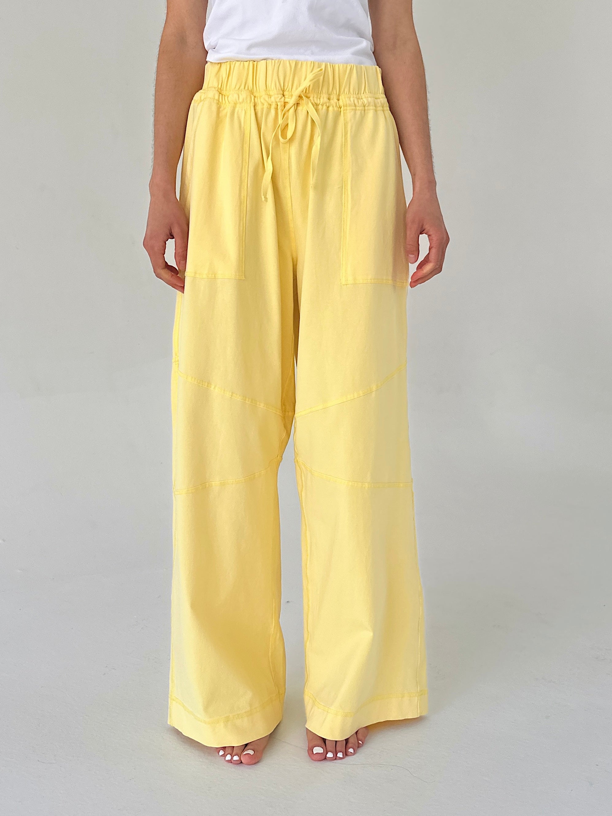 Person wearing yellow wide-leg pants on a plain background