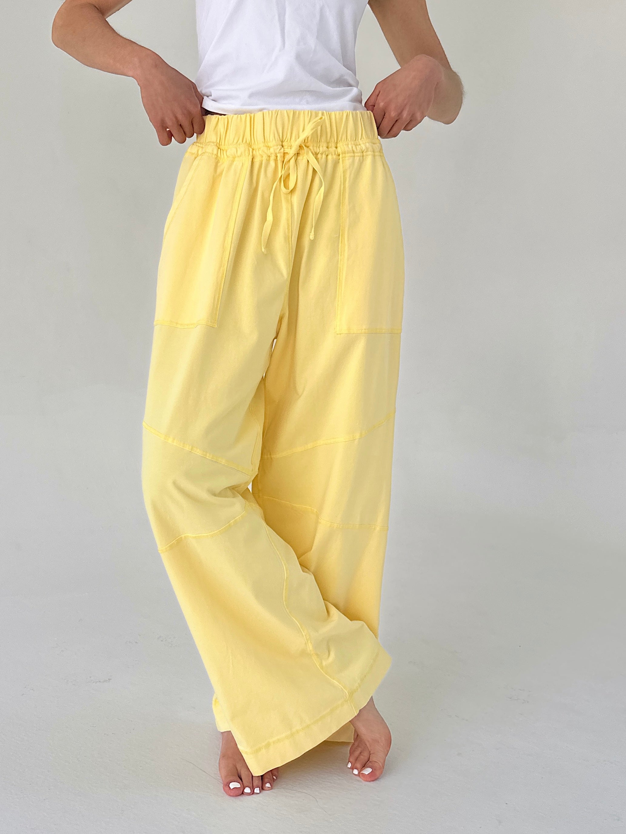 Person wearing yellow pants and a white top on a plain background