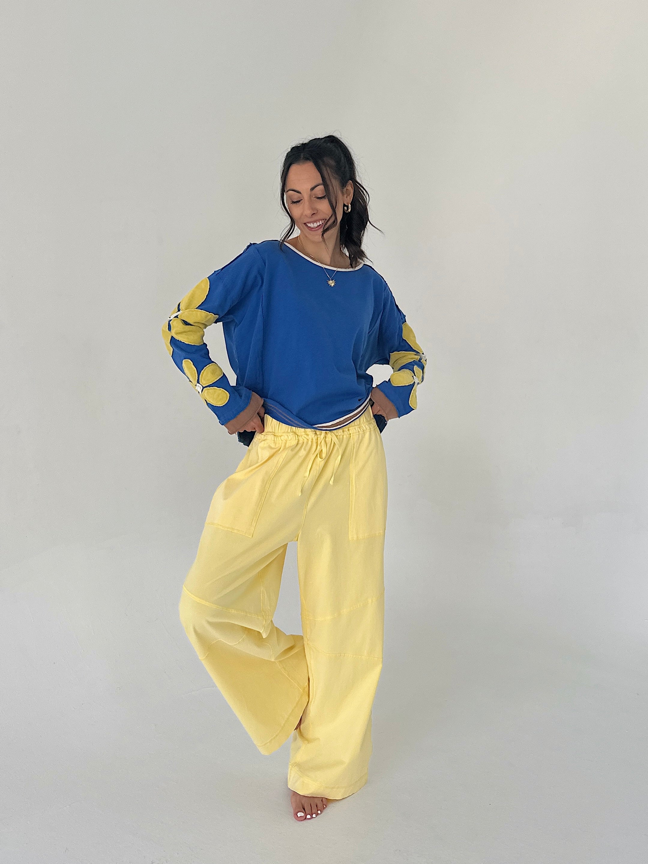 Person wearing a blue top with yellow sleeves and yellow pants on a plain background