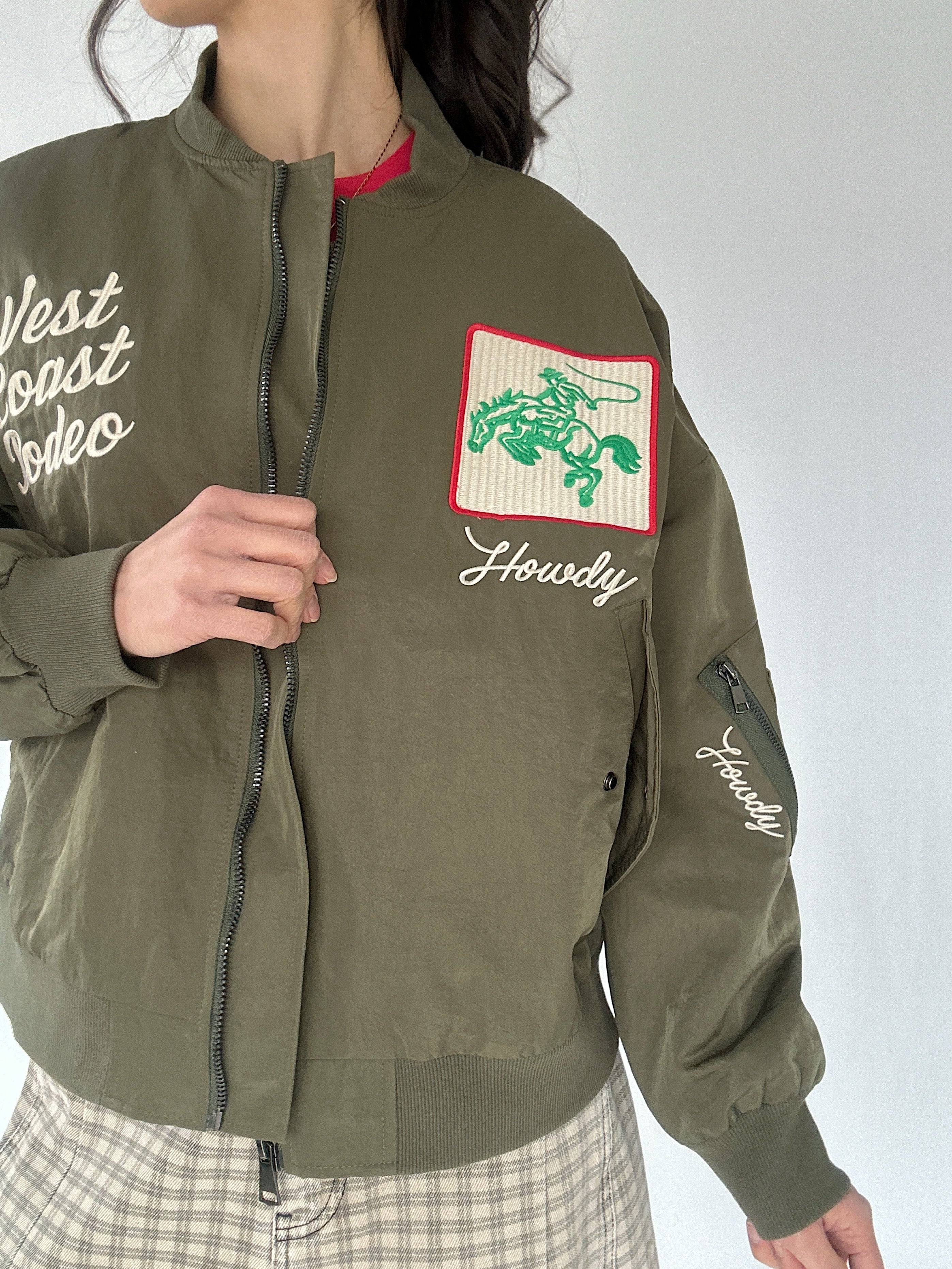 Green jacket with embroidered western designs on a plain background