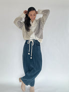 Woman wearing an argyle patterned sweater and blue pants on a white background