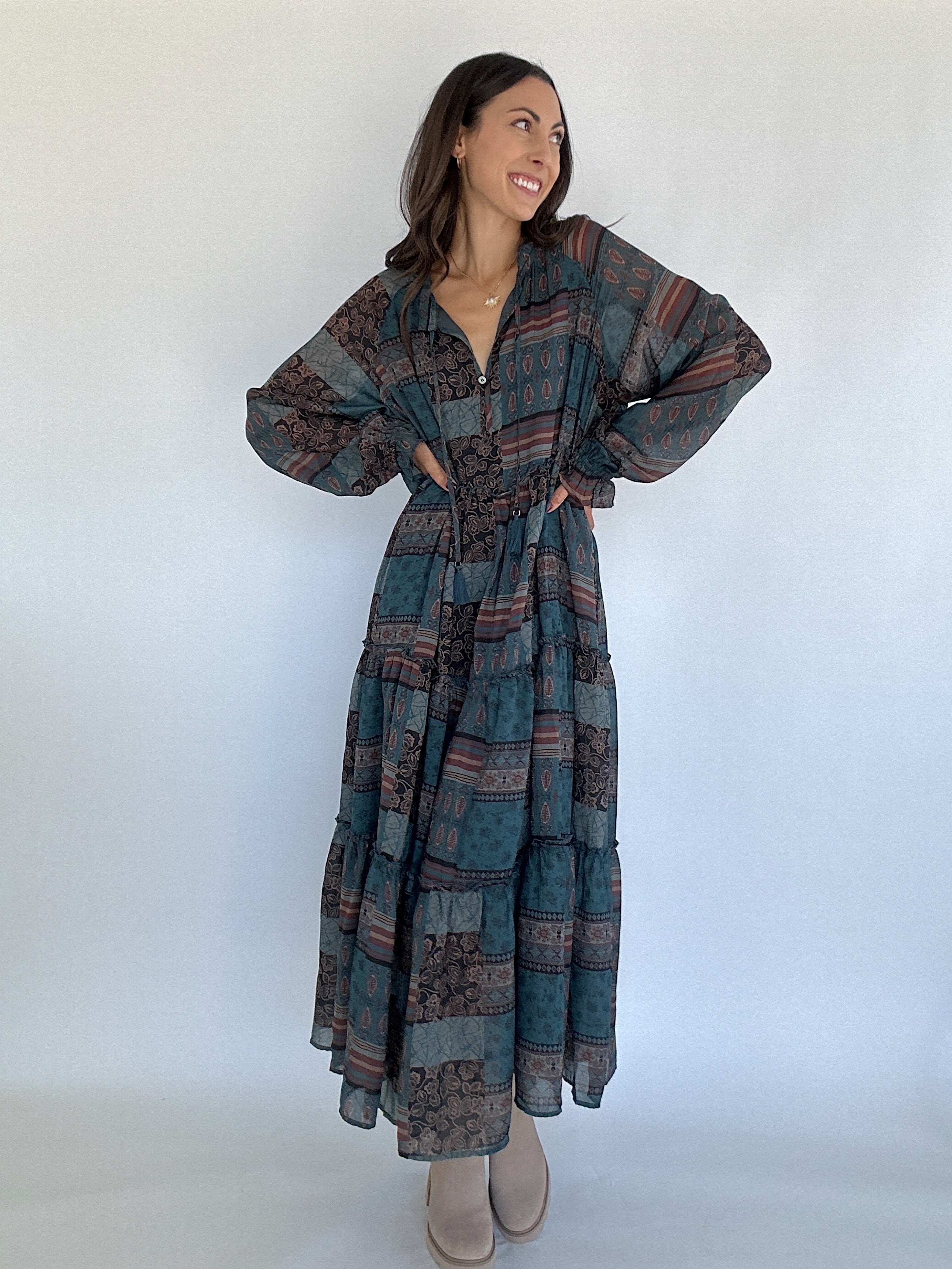 Woman wearing a long, patterned dress against a white background