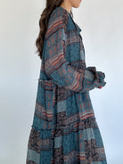 Long, patterned dress with a mix of blue and brown colors on a white background showing sleeve and side