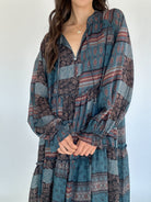 Woman wearing a long-sleeve, patterned dress against a white background showing neckline