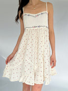 White floral dress with thin straps on a plain background