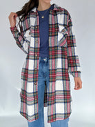 Person wearing a plaid coat over a blue shirt and jeans on a white background